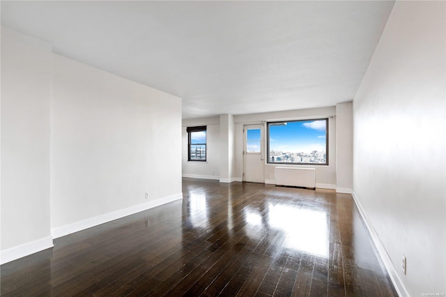 unfurnished room featuring radiator and dark hardwood / wood-style floors