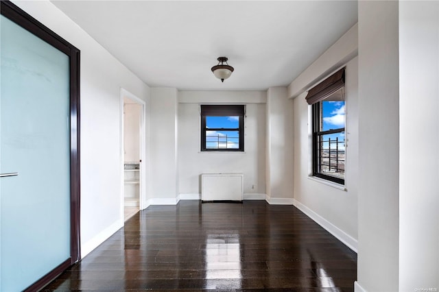 spare room featuring radiator heating unit and dark hardwood / wood-style flooring