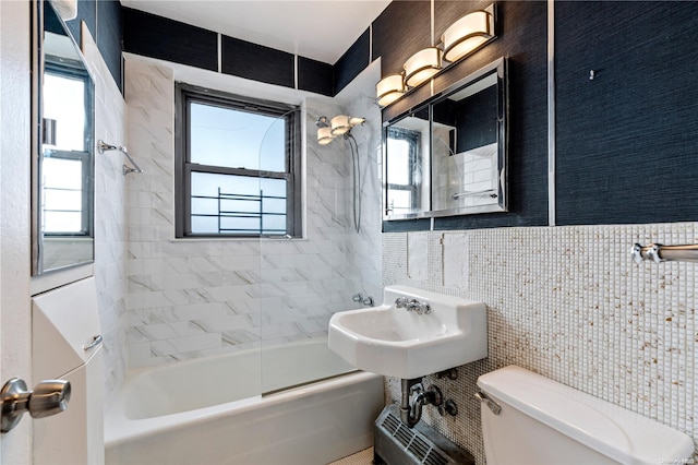 full bathroom with a wealth of natural light, tiled shower / bath combo, tile walls, and toilet