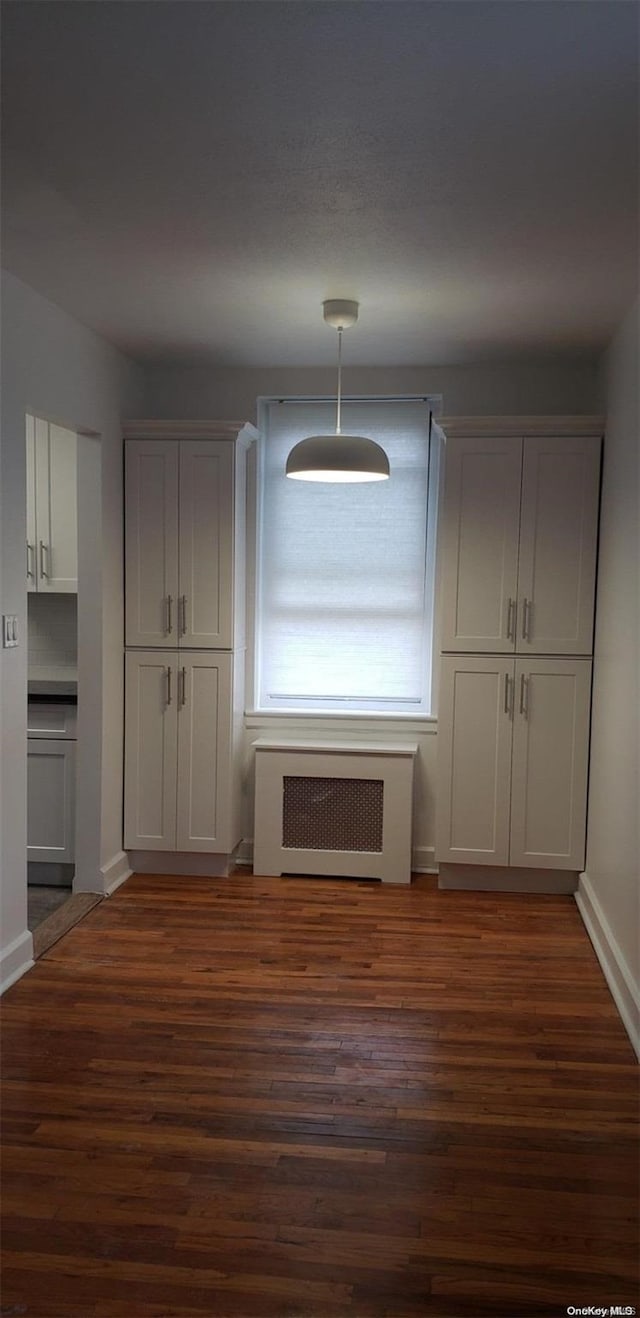 unfurnished dining area featuring radiator heating unit and dark hardwood / wood-style floors