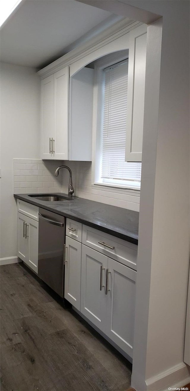 kitchen featuring tasteful backsplash, stainless steel dishwasher, sink, dark hardwood / wood-style floors, and white cabinetry