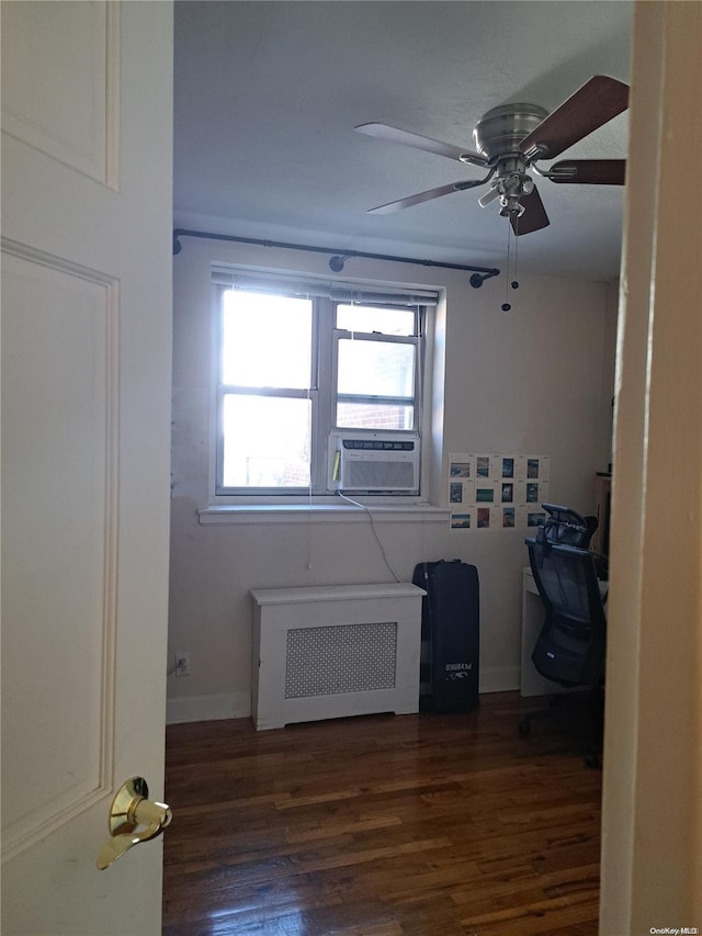 empty room featuring dark hardwood / wood-style floors, radiator, cooling unit, and ceiling fan