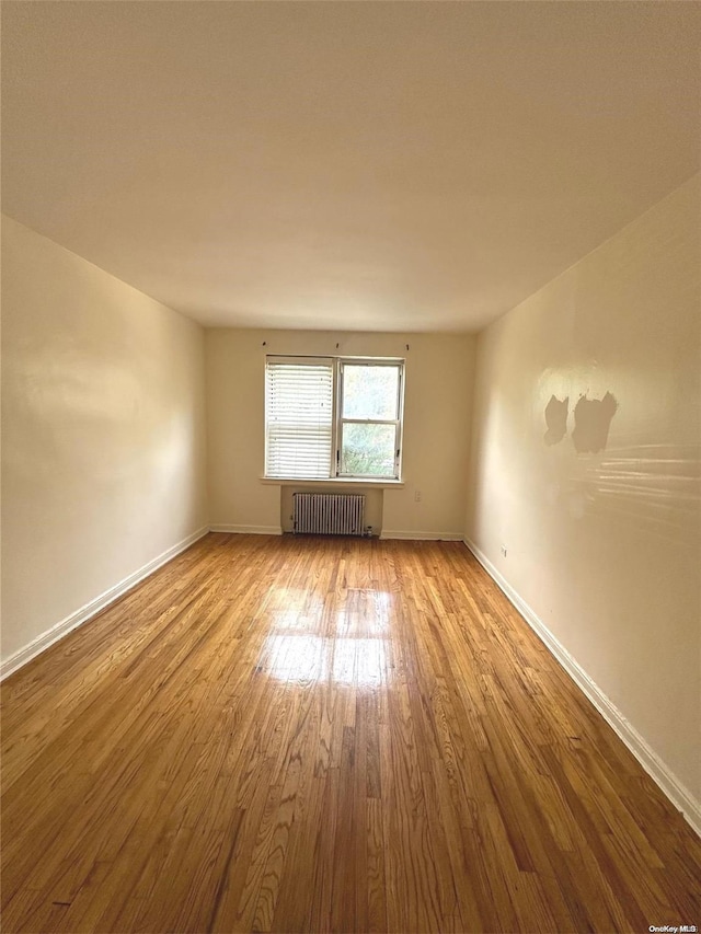 spare room featuring radiator heating unit and light hardwood / wood-style flooring