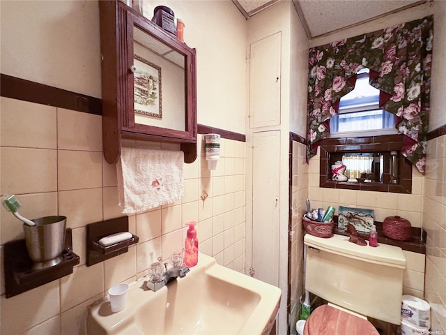 bathroom featuring sink, tile walls, and toilet