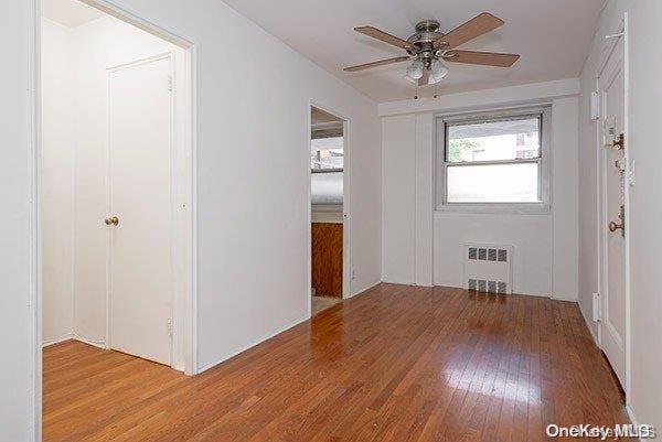 foyer entrance featuring hardwood / wood-style floors, ceiling fan, and radiator heating unit