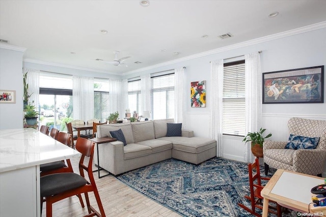 living room featuring ceiling fan, light wood-type flooring, and crown molding