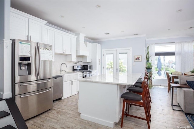 kitchen featuring white cabinets, a wealth of natural light, premium range hood, and appliances with stainless steel finishes