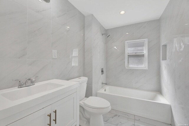 full bathroom featuring vanity, tiled shower / bath, tile walls, and toilet