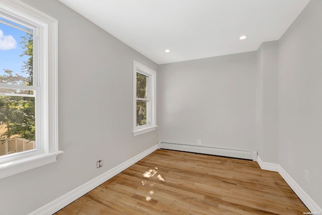 unfurnished room featuring light wood-type flooring and a baseboard radiator