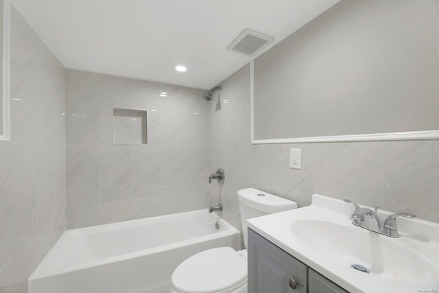 full bathroom with vanity, tiled shower / bath combo, tile walls, and toilet