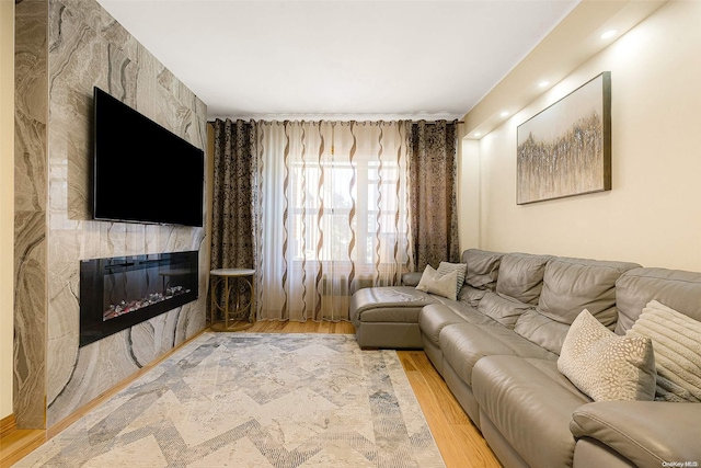 living room with a tiled fireplace and wood-type flooring