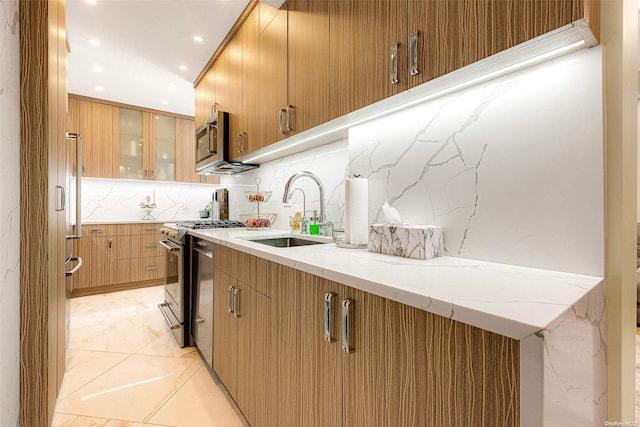 kitchen featuring stainless steel appliances, light stone counters, tasteful backsplash, and sink