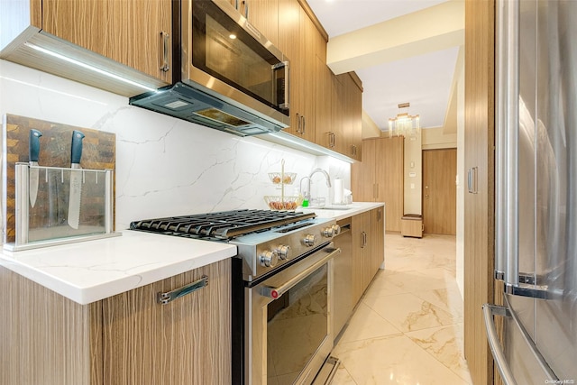 kitchen featuring light stone counters, sink, appliances with stainless steel finishes, and tasteful backsplash