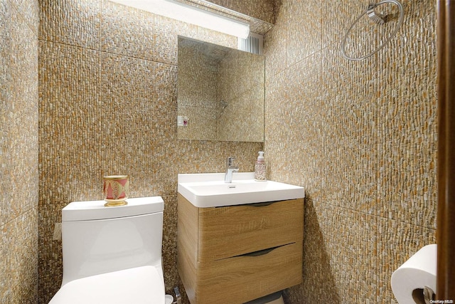 bathroom featuring vanity, tile walls, and toilet