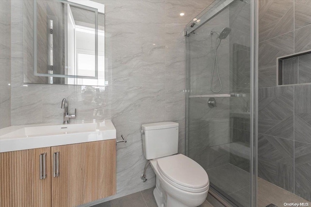 bathroom with walk in shower, vanity, tile walls, and toilet