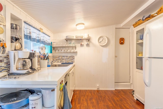 kitchen featuring decorative backsplash, crown molding, wooden walls, white fridge, and dark hardwood / wood-style floors