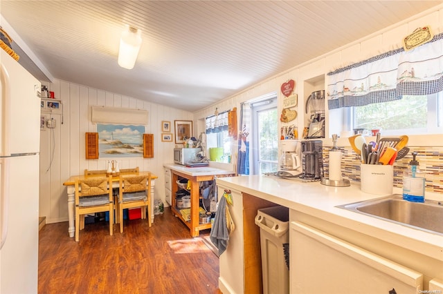 kitchen with vaulted ceiling, dark wood-type flooring, sink, white fridge, and wood walls