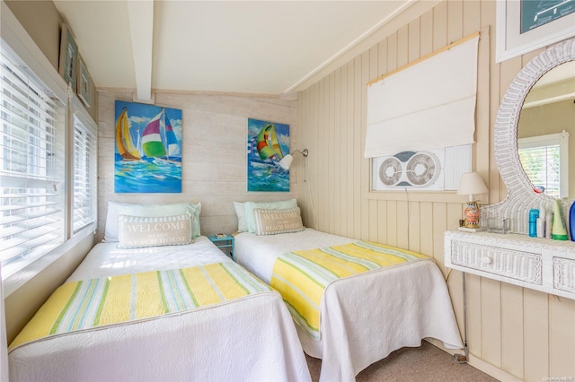 bedroom featuring carpet, wood walls, and beamed ceiling