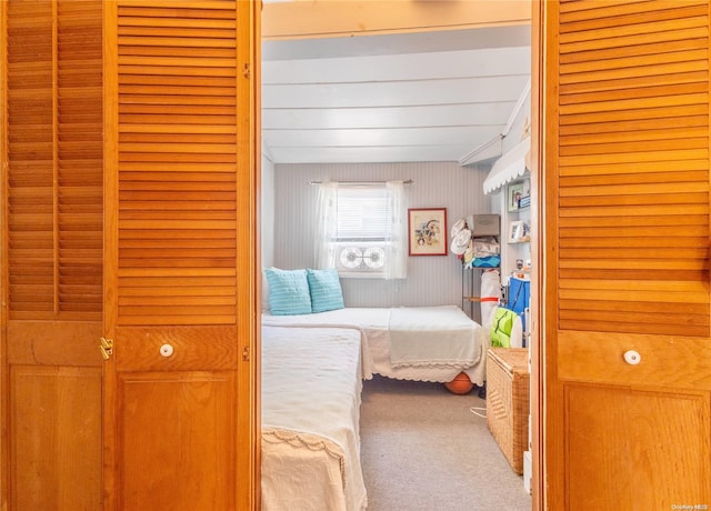 bedroom with wood walls, a closet, and light colored carpet