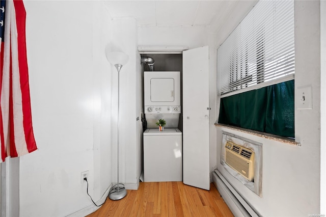 clothes washing area with light hardwood / wood-style flooring, stacked washer and clothes dryer, and a wall unit AC