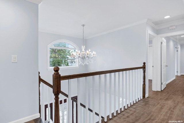 corridor featuring hardwood / wood-style flooring, crown molding, and an inviting chandelier