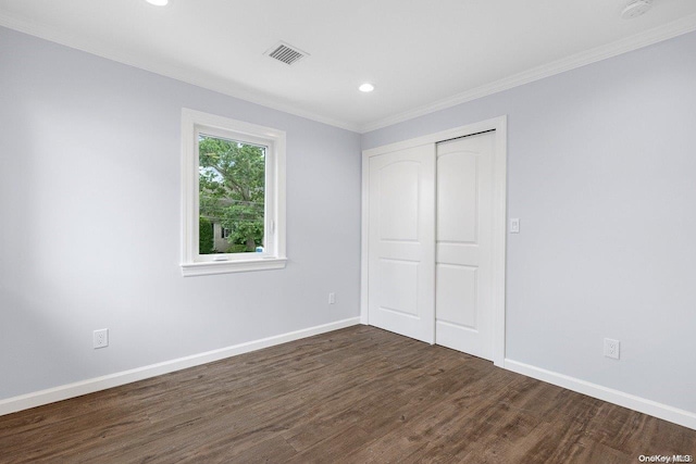 unfurnished bedroom with crown molding, a closet, and dark wood-type flooring