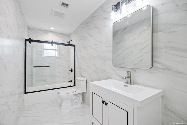 full bathroom featuring vanity, toilet, bath / shower combo with glass door, and tile walls