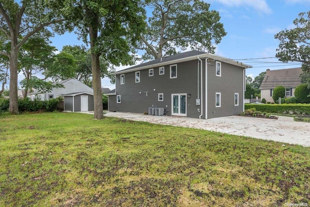 rear view of property featuring central air condition unit, a storage unit, and a lawn