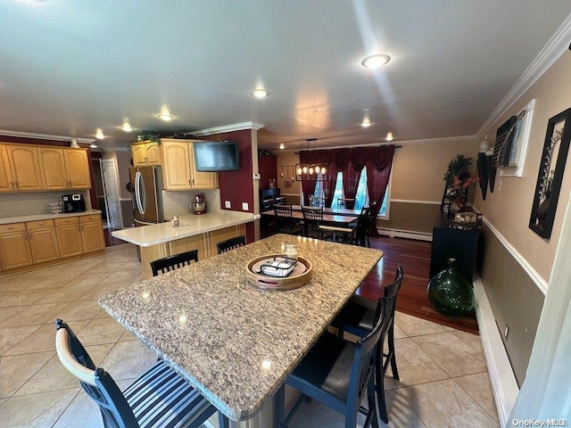 kitchen featuring a large island, stainless steel fridge, a breakfast bar area, light tile patterned flooring, and ornamental molding