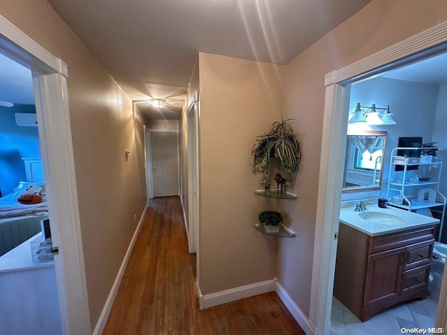 corridor featuring a wall unit AC, light hardwood / wood-style flooring, and sink