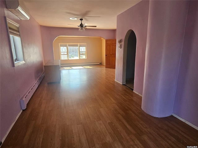 empty room featuring a wall mounted air conditioner, hardwood / wood-style floors, baseboard heating, and ceiling fan