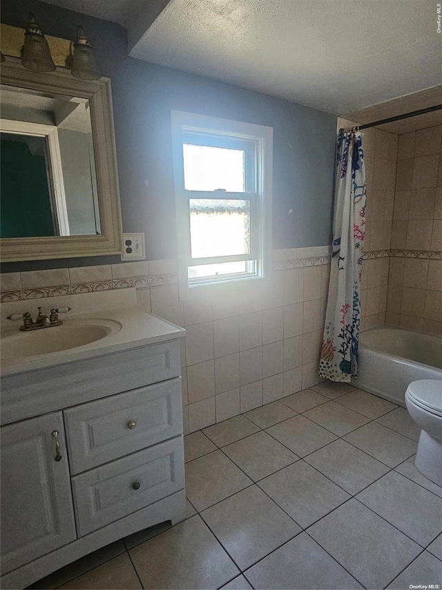 full bathroom with a textured ceiling, tile patterned floors, tile walls, and shower / bath combo with shower curtain