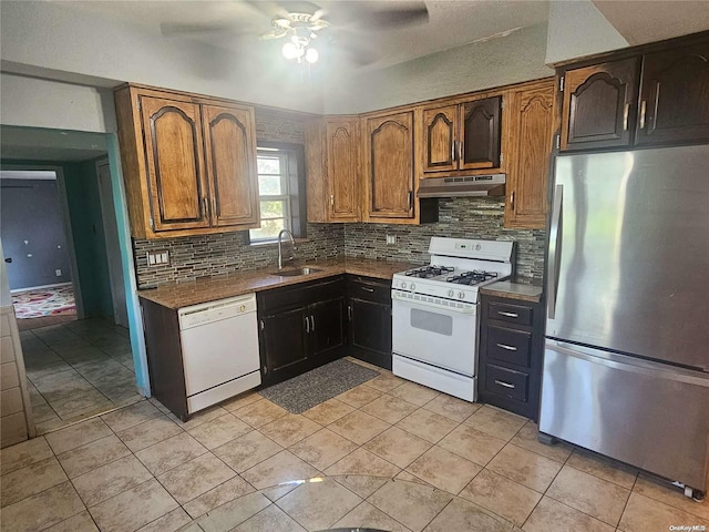 kitchen featuring decorative backsplash, white appliances, ceiling fan, sink, and dark stone countertops