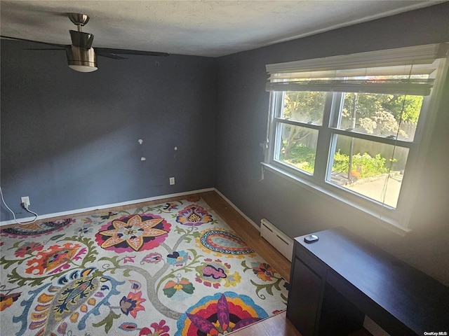 unfurnished room featuring baseboard heating and hardwood / wood-style floors