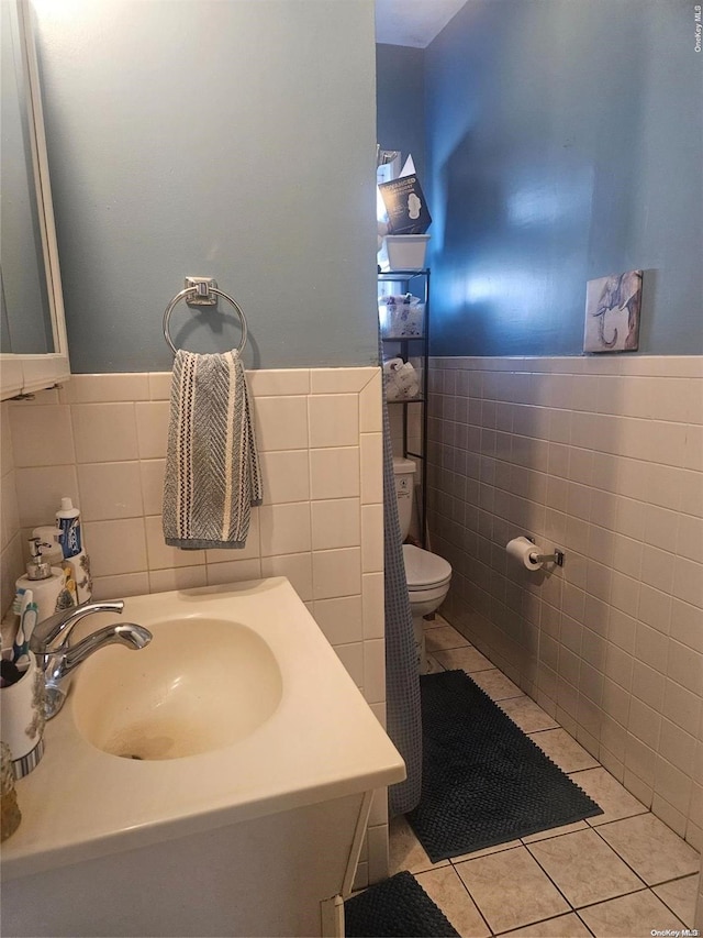 bathroom with tile patterned floors, toilet, sink, and tile walls