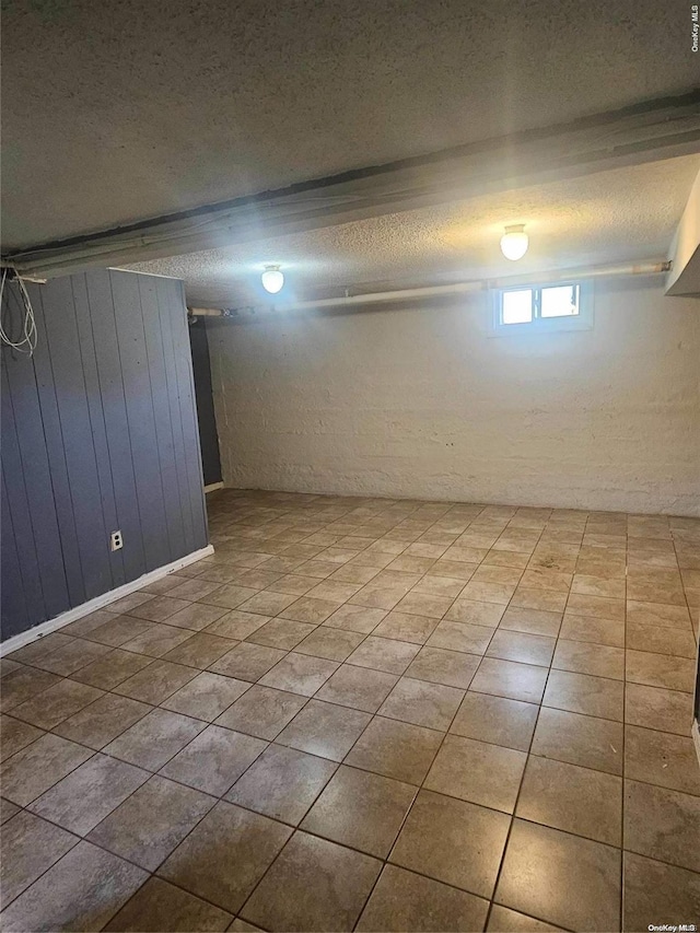 basement featuring tile patterned flooring and a textured ceiling