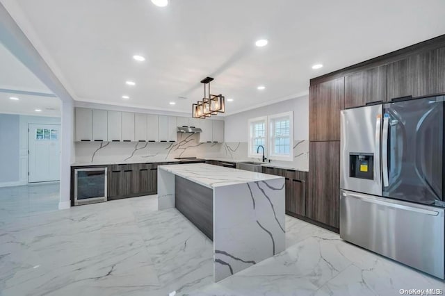 kitchen with wine cooler, stainless steel fridge with ice dispenser, light stone counters, decorative light fixtures, and a kitchen island