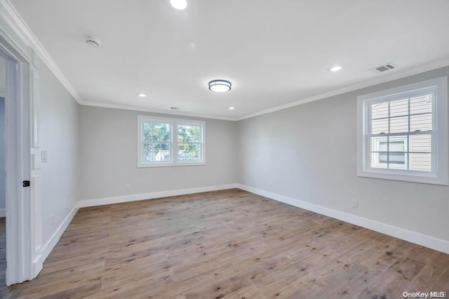 spare room featuring a healthy amount of sunlight, light wood-type flooring, and ornamental molding