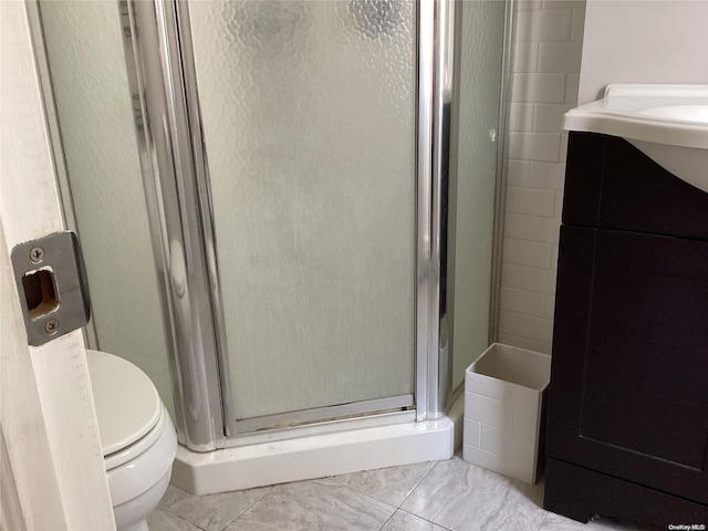 bathroom featuring tile patterned flooring, vanity, toilet, and walk in shower