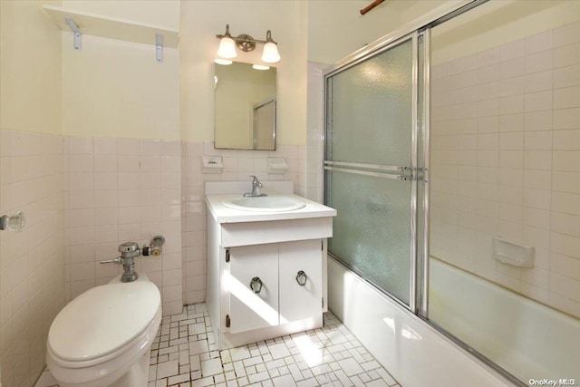 full bathroom featuring vanity, bath / shower combo with glass door, tile patterned flooring, toilet, and tile walls