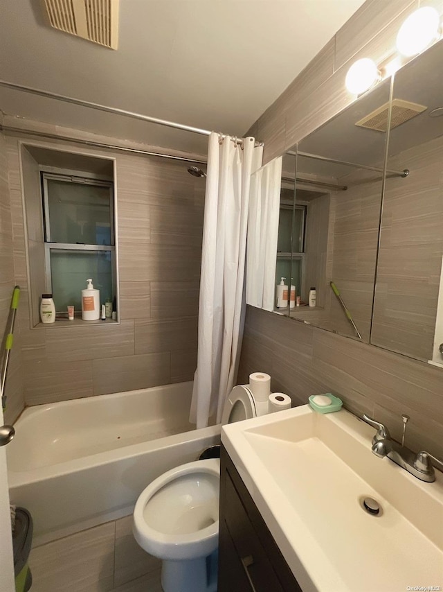 full bathroom with tasteful backsplash, toilet, shower / tub combo with curtain, vanity, and tile walls