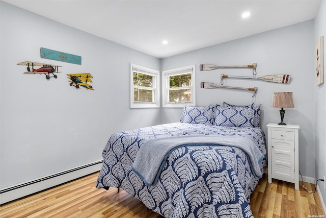 bedroom featuring baseboard heating and hardwood / wood-style flooring