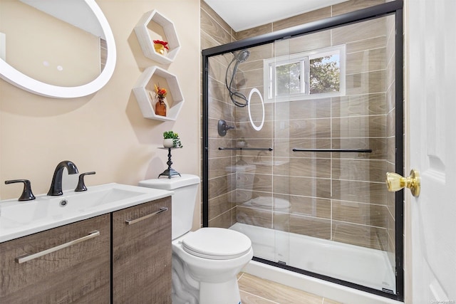 bathroom with vanity, toilet, and a shower with shower door