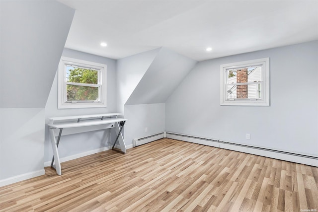 additional living space featuring a baseboard heating unit, light wood-type flooring, vaulted ceiling, and a healthy amount of sunlight