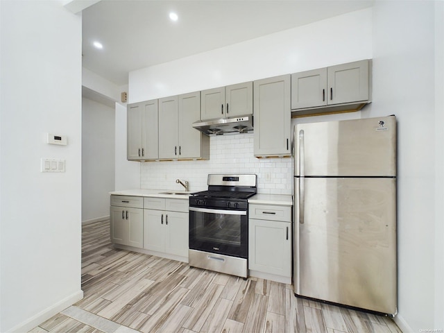 kitchen with appliances with stainless steel finishes, tasteful backsplash, gray cabinetry, sink, and light hardwood / wood-style flooring