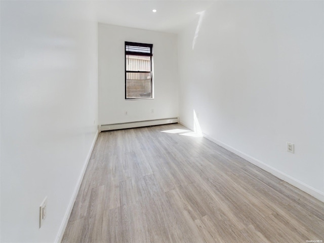 spare room featuring light wood-type flooring and a baseboard heating unit