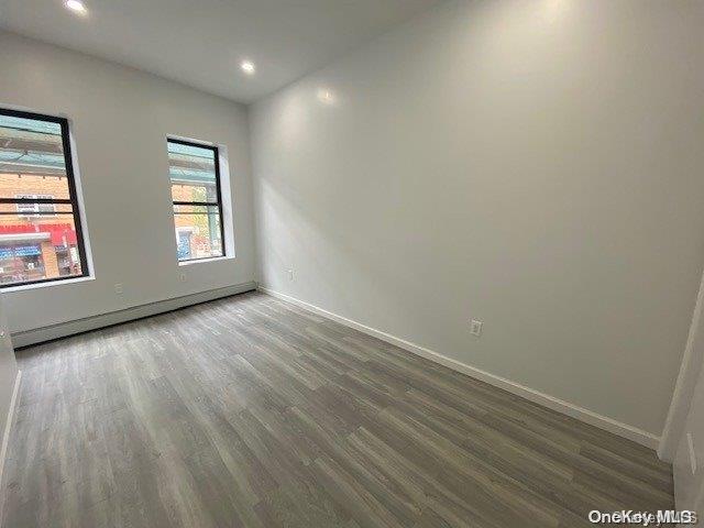 empty room with hardwood / wood-style flooring and a baseboard radiator