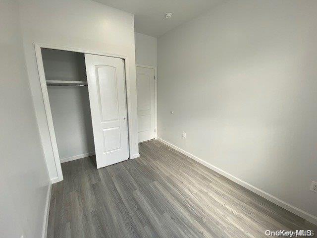 unfurnished bedroom with dark hardwood / wood-style flooring and a closet