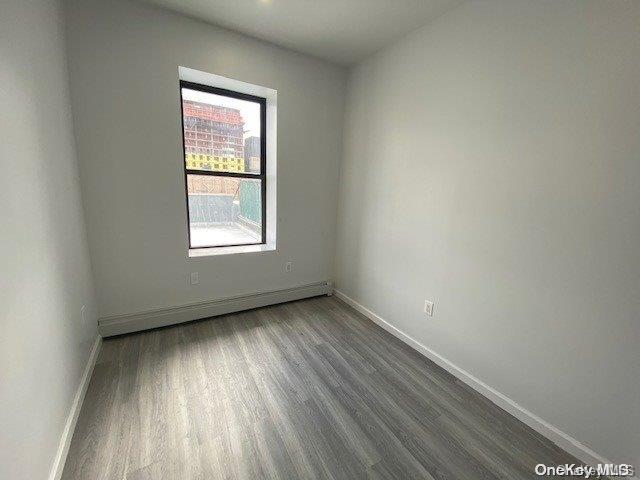 spare room with a baseboard radiator and dark wood-type flooring