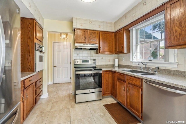 kitchen with decorative backsplash, sink, light tile patterned floors, and appliances with stainless steel finishes